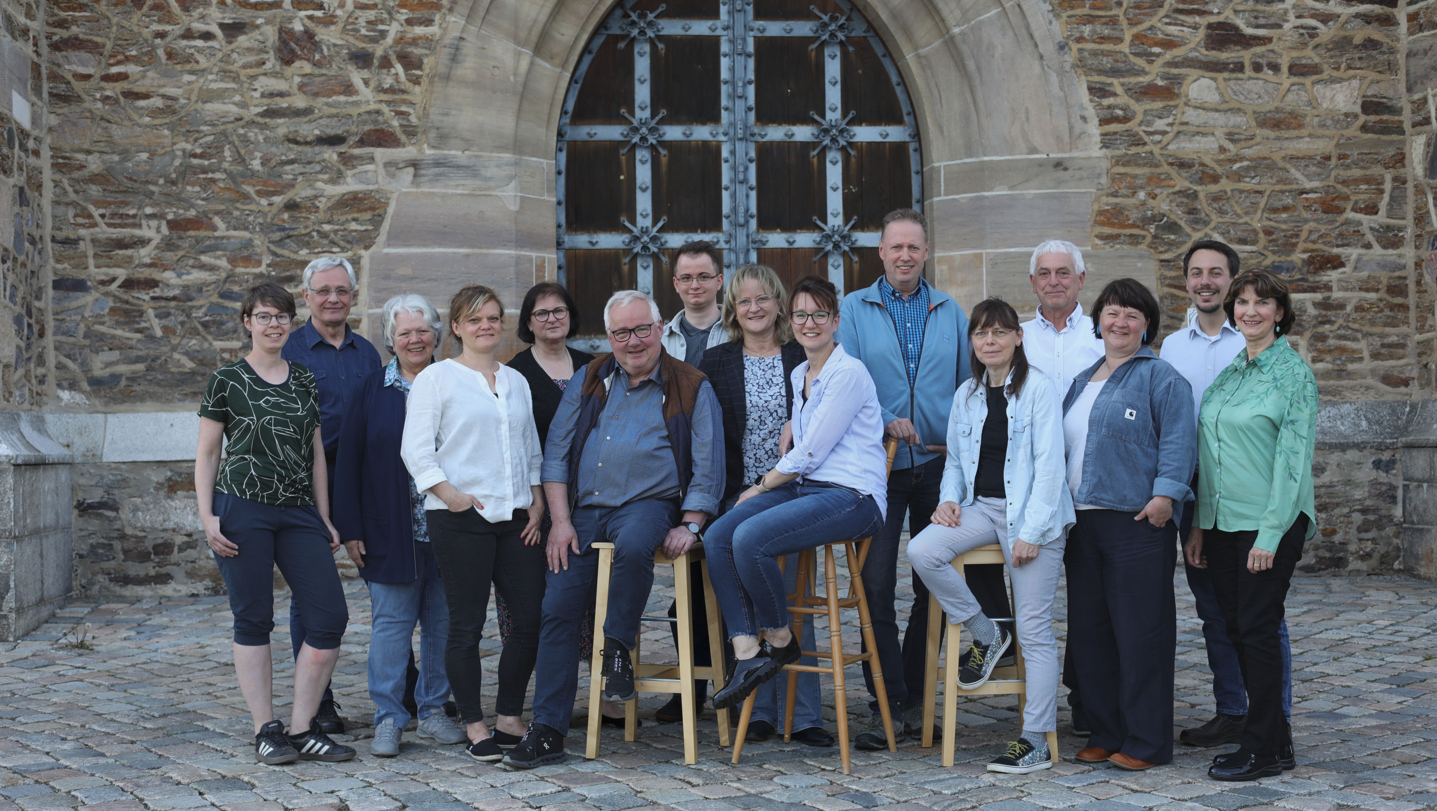 Gruppenporträt des Kirchenvorstands vor einem steinernen Kirchenportal.